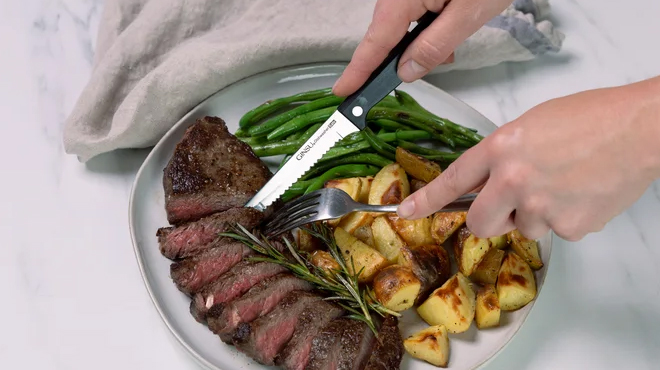 Person using the Ginzu knife to cut the steak