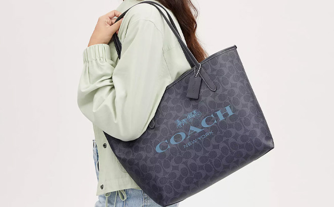Woman is Holding Coach City Tote In Signature Canvas in Midnight Navy Color