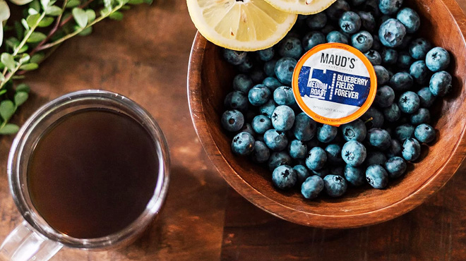 A cup of Coffee Beside a Mauds Blueberry Coffee Pod a Bowl of Blueberries