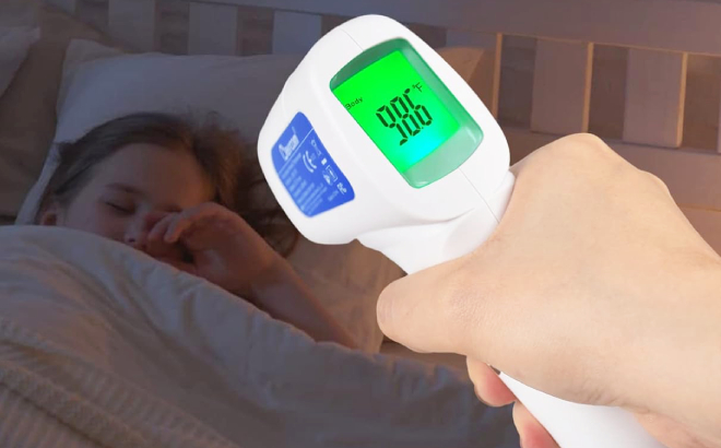 Lady Checking the Sleeping Girls Temperature Using a Berrcom Infrared Forehead Thermometer