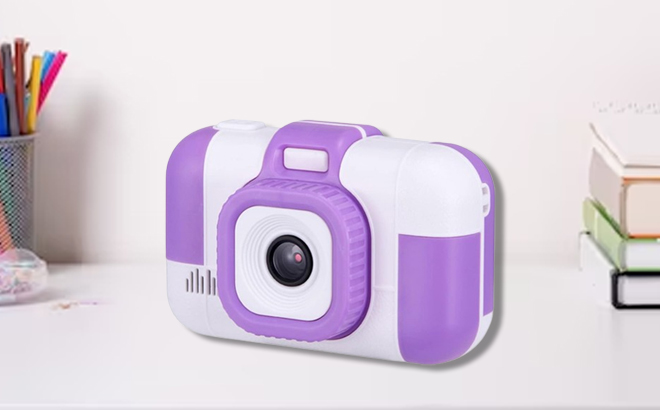 SunChen Kids Digital Camera in Purple Color on the table with books and pens on the side