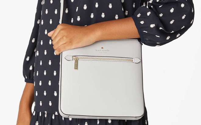 Woman is Holding Kate Spade Sadie North South Crossbody in Platinum Grey Color