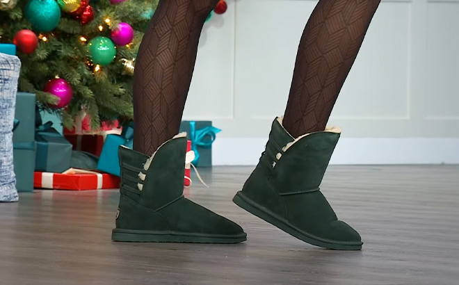 Woman is Wearing Bearpaw Kylee Suede Water and Stain Repellent Boots in Dark Green Color