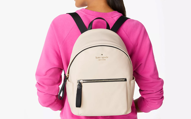 Woman is Wearing Kate Spade Chelsea Medium Backpack in Warm Beige Multi Color