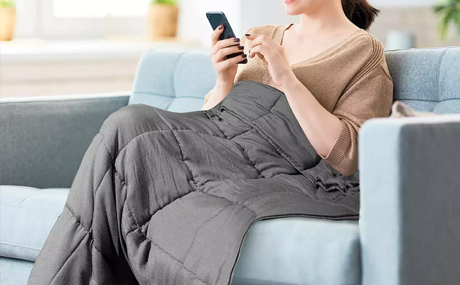 a Woman Sitting on a Couch and Covered with Weighted Blanket