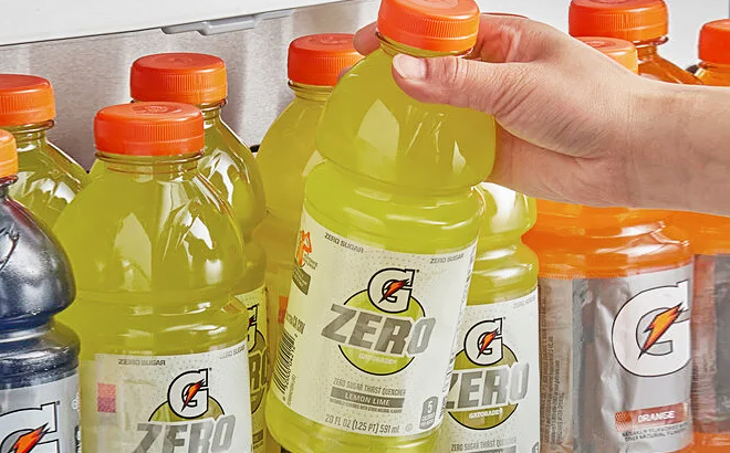 A Hand Grabbing Gatorade Zero Sugar Thirst Quencher in Lemon Lime from a Shelf Filled with Gatorade