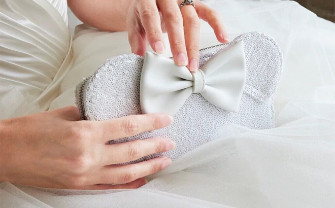 A Person Holding the Loungefly Disney Minnie Sequin Wedding Zip Around Wallet in the Color White