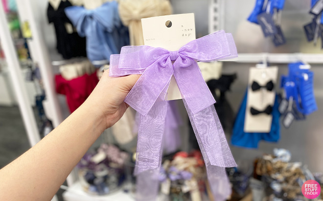 Hand Holding A New Day Bow Hair Clip in Violet Color