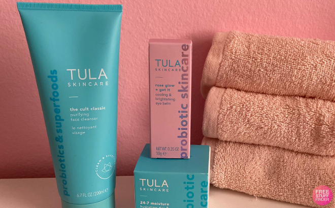 Tula Skincare Rose Glow Get It Cooling Brightening Eye Balm on a Table with a Towels and Other Tula Products