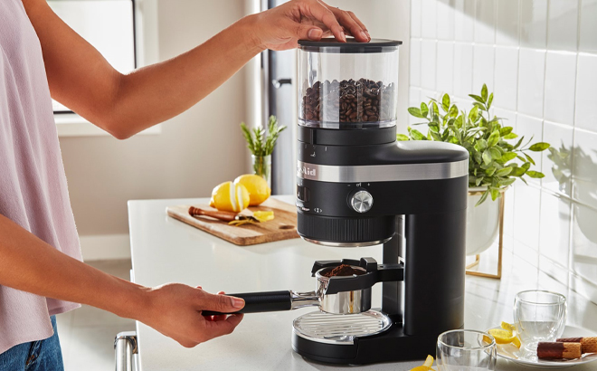 Woman Using the KitchenAid Burr Coffee Grinder in Matte Black