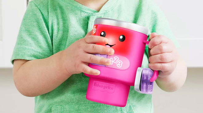 A Child Holding a Fisher Price Laugh Learn Wake Up Learn Coffee Mug