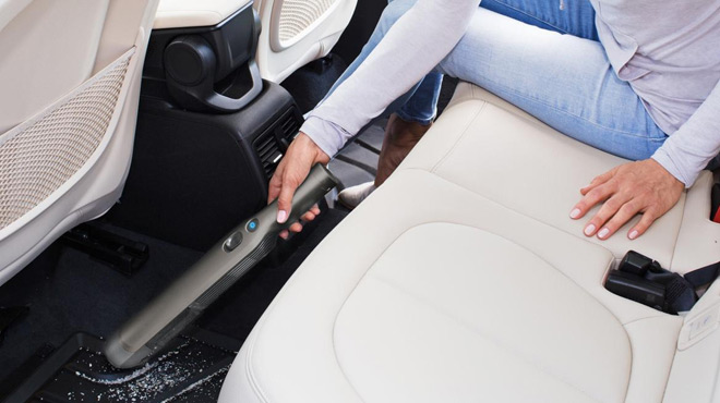 A Person Cleaning the Car Floor using Shark WANDVAC Cord Free Handheld Vacuum