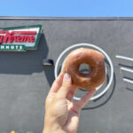 A Person Holding a Krispy Kreme Original Glazed Doughnut