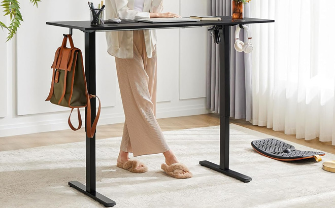 A Person Standing beside a Smug Adjustable Electric Standing Desk in Black