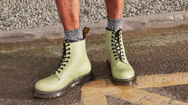 A Person Wearing a Pair of Dr Martens Lace Up Boots in Pale Olive