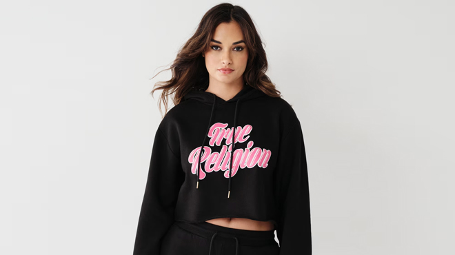 A Woman Wearing True Religion Logo Crop Hoodie in Black Color