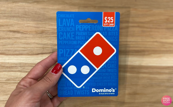 Hand Holding a 25 Dominos Gift Card on a Table