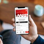 Hand Holding a Phone with AARP Membership on the Background