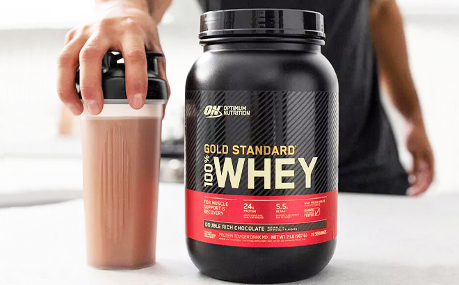 Optimum Nutrition Gold Standard 100 Whey Protein Powder Double Rich Chocolate with a person holding the tumbler