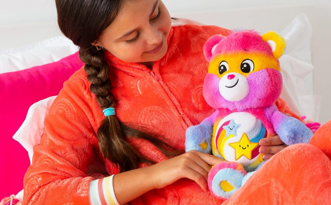 A Person Carrying a Care Bears Dare to Tie Dye 14 Inch Plush on Her Lap