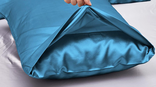 A Person Holding a Satin Pillowcase on a Bed