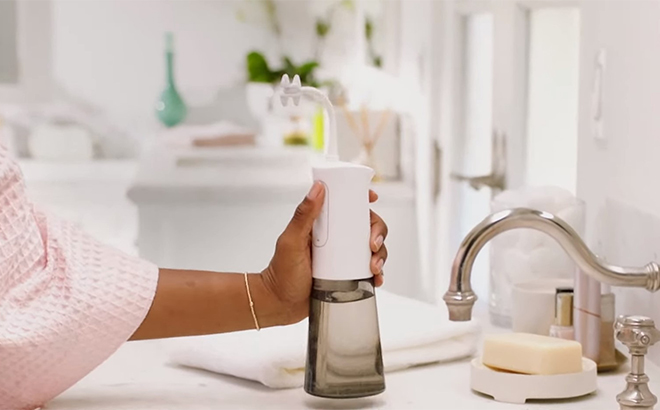 A Person Holding the Miracle Smile Deluxe Pro Water Flosser in a Bathroom