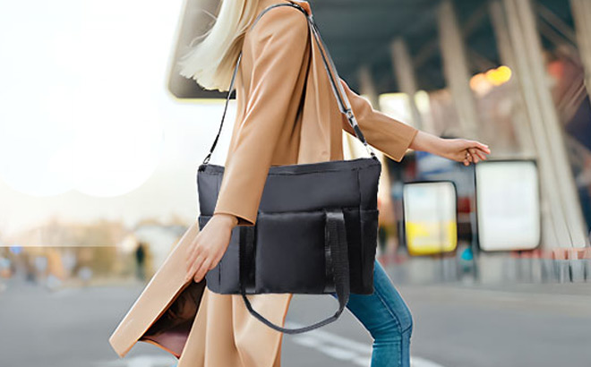 A Person Walking on The Street with a Travel Tote Bag in Black Color on Her Shoulder