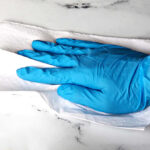 A Man Cleaning a Marble Countertop Using 4Mil Blue Nitrile Gloves