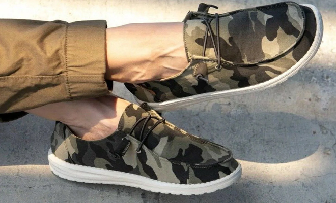 A Person Wearing the Hey Dude Womens Wendy Sox Slip on Loafers in the Retired Camo Pattern