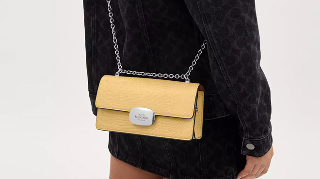 A Woman Wearing Coach Outlet Eliza Flap Crossbody Bag in Hay