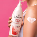 A lady holding a Jergens Original Scent Dry Skin Body Lotion