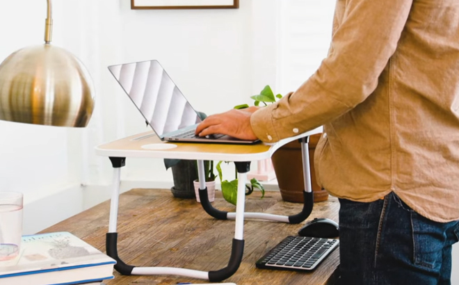 A person working on his laptop using a Tech Impressions Portable Laptop Desk 1