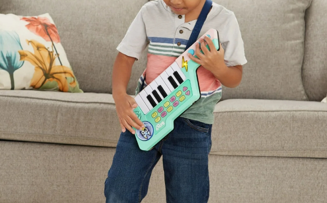 A Boy Playing with VTech Bluey Keytar Toy Piano and Guitar Combo