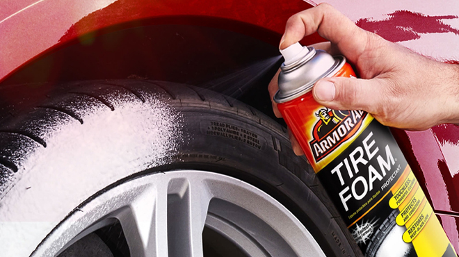 A Hand spraying Armor All Tire Foam Automotive Protectant Foam on a Tire