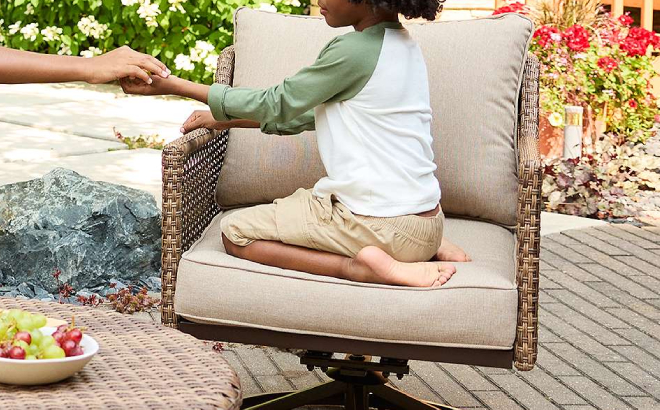 A Kid Sitting on a Sonoma Goods For Life Benton Wicker Swivel Chair