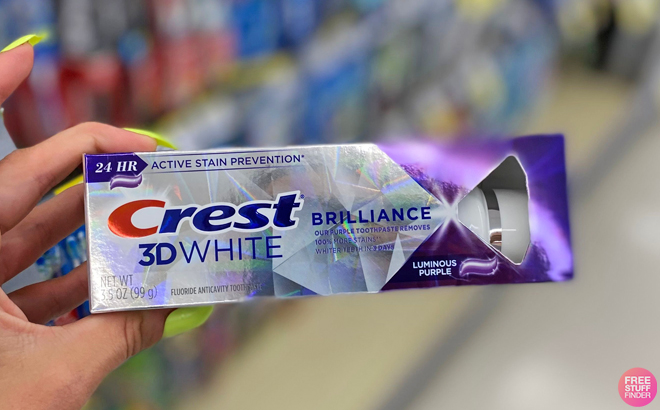 A Person Holding a Crest 3D White Brilliance Luminous Purple Teeth Whitening Toothpaste