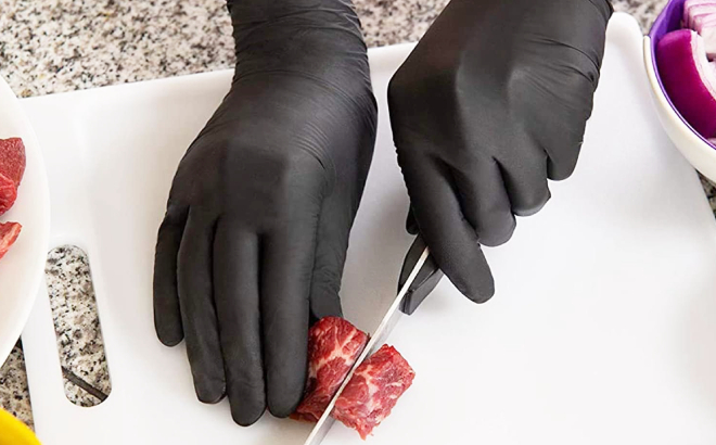A Person Slicing Beef wth Nitril Gloves on