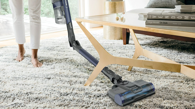 A Person Using a Shark Pet Pro Cordless Stick Vacuum to Clean a carpet rug