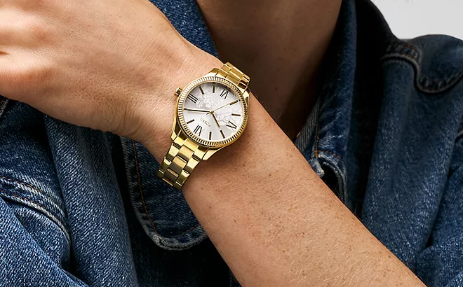 A Person Wearing a Fossil Rye Three Hand Gold Tone Alloy Watch