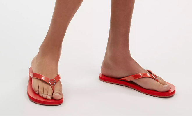 A Person Wearing the Coach Outlet Zayn Flip Flops in Red