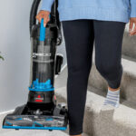 A Person carrying Bissell Upright Vacuum