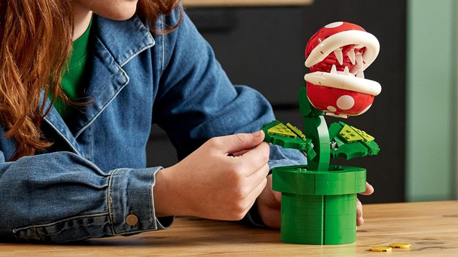 A person building a LEGO Super Mario Piranha Plant