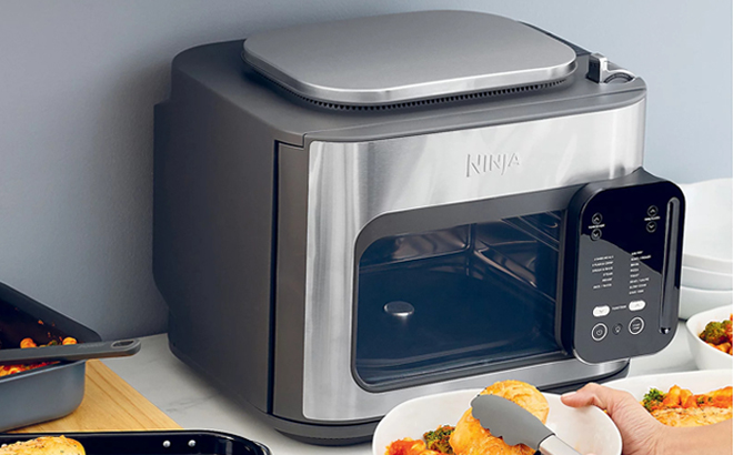 Ninja Combi All in One Multicooker on a Kitchen counter next to the Plates with Food