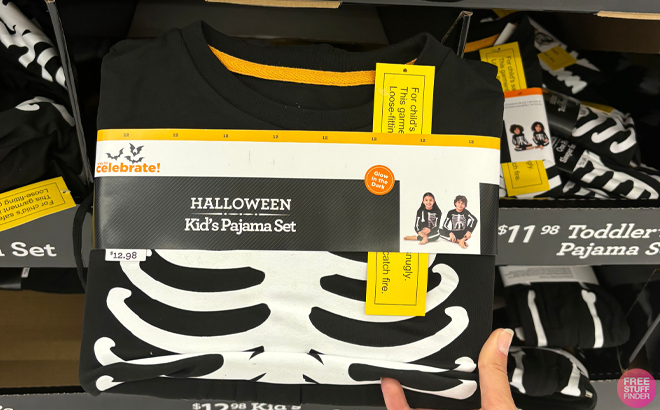 A Hand holding Halloween Kids Glow In The Dark Skeleton Pajama Set