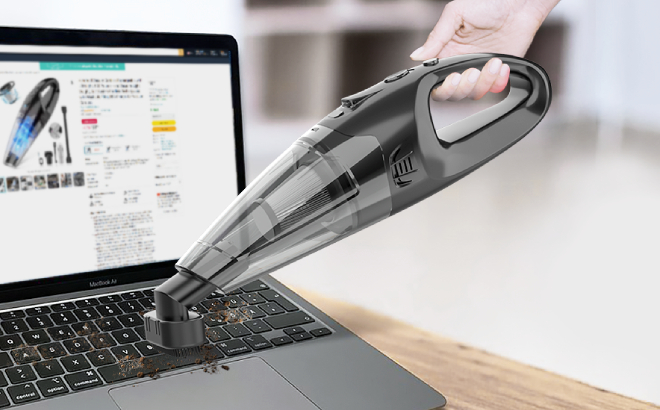 A Person Cleaning a Laptop Keyboard Using a Handheld Cordless Vacuum