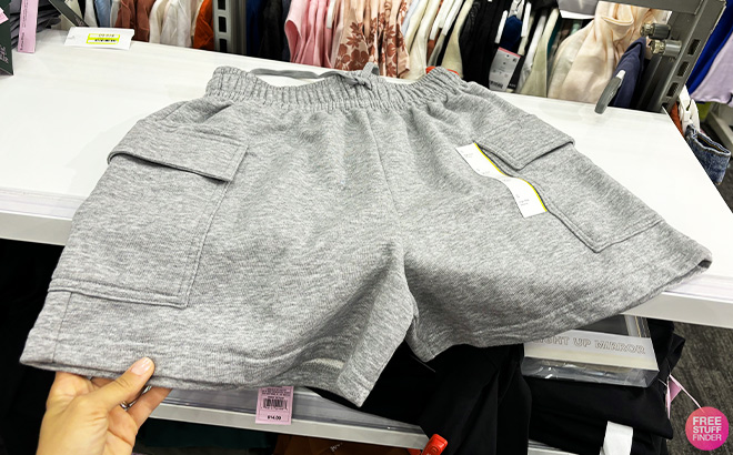 A Person Holding Wild Fable Womens Mid Rise Cargo Sweat Shorts in Heather Gray Color