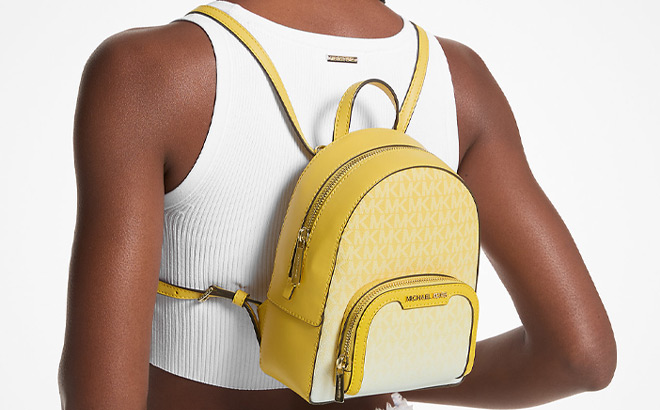 A Person Wearing Michael Kors Jaycee Extra Small Ombre Logo Convertible Backpack in Yellow Color