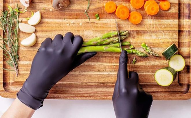 A Person cutting vegetables with Black Gloves on