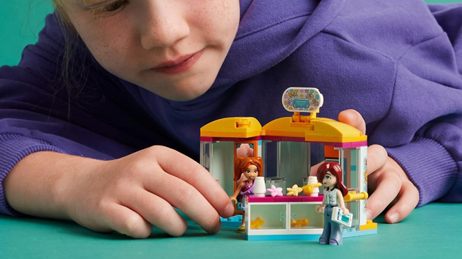 A Person playing with LEGO Friends Tiny Accessories Store and Beauty Shop Building Set