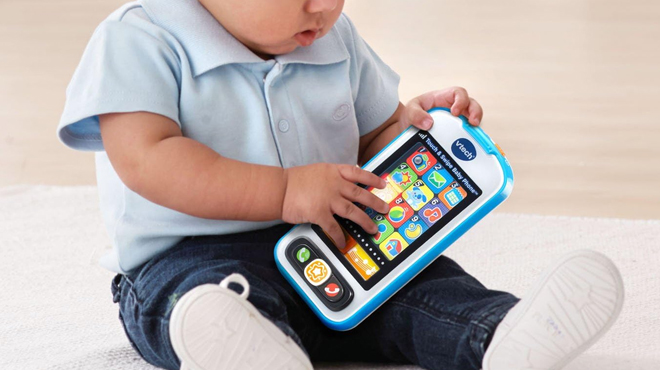 A Toddler Holding a VTech Touch and Swipe Baby Phone